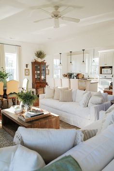 a living room filled with white furniture and lots of pillows on top of it's couches