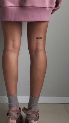 the back of a woman's legs with small tattoos on her left leg and right leg