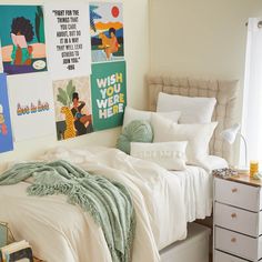 a bedroom with white bedding and posters on the wall above it's bed