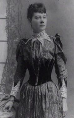 an old black and white photo of a woman wearing a dress with lace on it