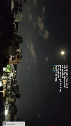 an aerial view of a city at night with the moon in the sky above it