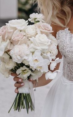 a bride holding a bouquet of white and pink flowers