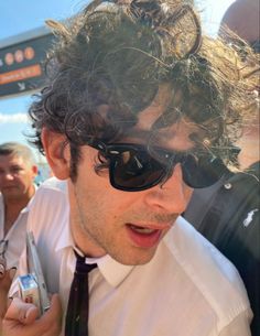 a man with curly hair wearing sunglasses and a tie