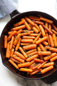 a pan filled with carrots sitting on top of a counter next to a blue towel