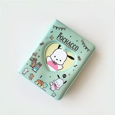 a hello kitty brooch sitting on top of a green book with animals around it