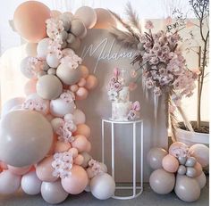 the balloon arch is decorated with pink and white balloons, flowers, and greenery