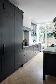 a large kitchen with black cabinets and white counter tops, along with an island in the middle