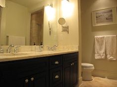 a bathroom with two sinks, a toilet and a large mirror above the vanity area