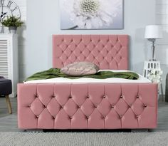 a pink bed with buttons on the headboard and foot board is in a room