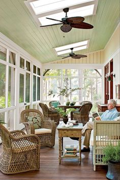 an older man sitting on a porch with wicker furniture and ceiling fan above him