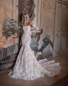 a woman standing in front of a painting wearing a wedding dress