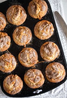 freshly baked muffins on a baking tray with a knife and fork next to them