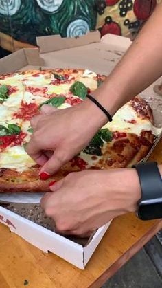 a person cutting into a pizza on top of a wooden table