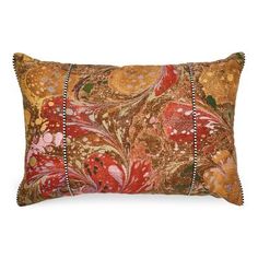 an orange and red pillow with beaded trims on the edges, sitting on a white background