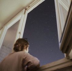 a woman looking out the window at the stars