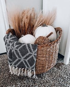 a basket filled with white pumpkins sitting on top of a carpet next to a door