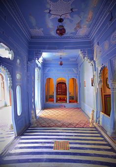 an ornate hallway with blue walls and striped flooring, painted in bright colors is shown