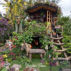 an outdoor garden with lots of plants and flowers on the ground, including a tree house