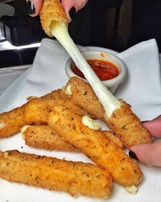 someone is dipping sauce on some deep fried fish sticks with cheese and ketchup