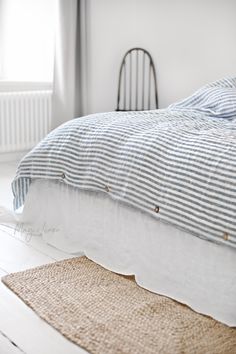 an unmade bed with blue and white striped sheets