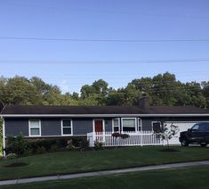 a black truck parked in front of a house with a white picket fence and trees