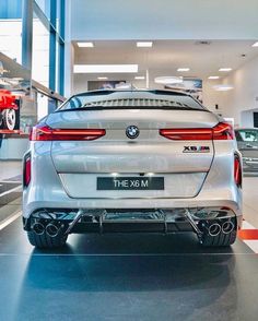 the rear end of a white bmw car in a showroom