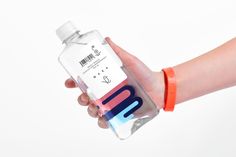 a hand holding a water bottle with an orange band around it's wrist and label on the side