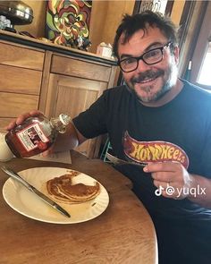 a man sitting at a table with pancakes and syrup