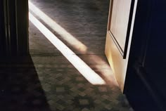 an open door leading into a hallway with tiled flooring and white walls on either side