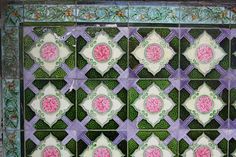 an artisticly designed tile with pink flowers on it's sides and green leaves