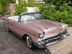 an old pink car is parked in the driveway