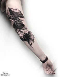 a woman's arm with black and white tattoos on her left hand, holding a flower