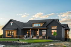 a black house with lots of windows on the front and side of it, surrounded by grass