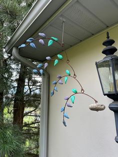 a lamp hanging from the side of a house next to a tree branch with leaves on it