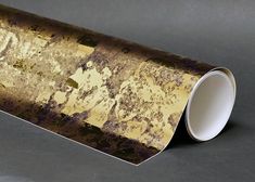 a roll of gold foil with brown and black spots on the side, sitting on a table