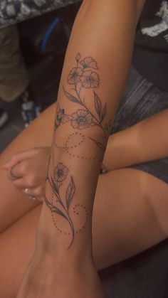 a woman's arm with flowers on it and dots in the middle, while she is sitting down