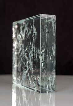 a glass block sitting on top of a white table next to a black wall behind it