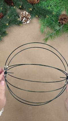 someone is making a wire wreath with pine cones