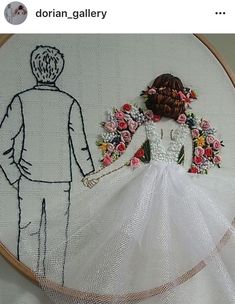 a man and woman standing next to each other in front of a cross stitch wedding dress