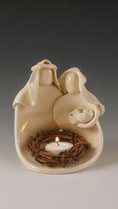 a small ceramic candle holder with two doves and a bird nest on the base