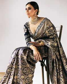 a woman sitting on top of a chair wearing a gold and blue sari dress