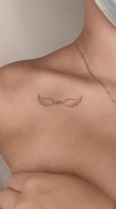 the back of a woman's chest with an angel wing tattoo on her left shoulder