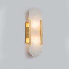 a light that is on the side of a wall with a white and gold finish