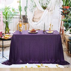 a purple table cloth on top of a wooden floor in front of potted plants