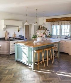 a large kitchen with an island in the middle and two stools at the end