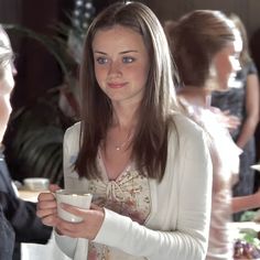 a woman standing next to another woman holding a cup