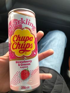 a person holding up a can of chupa chups strawberry and cream flavored drink