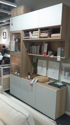 a white couch sitting in front of a book shelf filled with books and other items