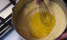 a person mixing food in a bowl on top of a stove with a whisk