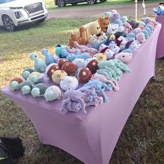 there are many stuffed animals on the table at this outdoor event that is ready to be sold